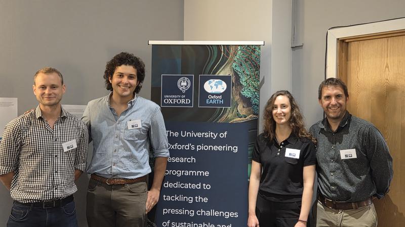 Four Oxford EARTH Research Fellows standing in front of an Oxford EARTH branded banner
